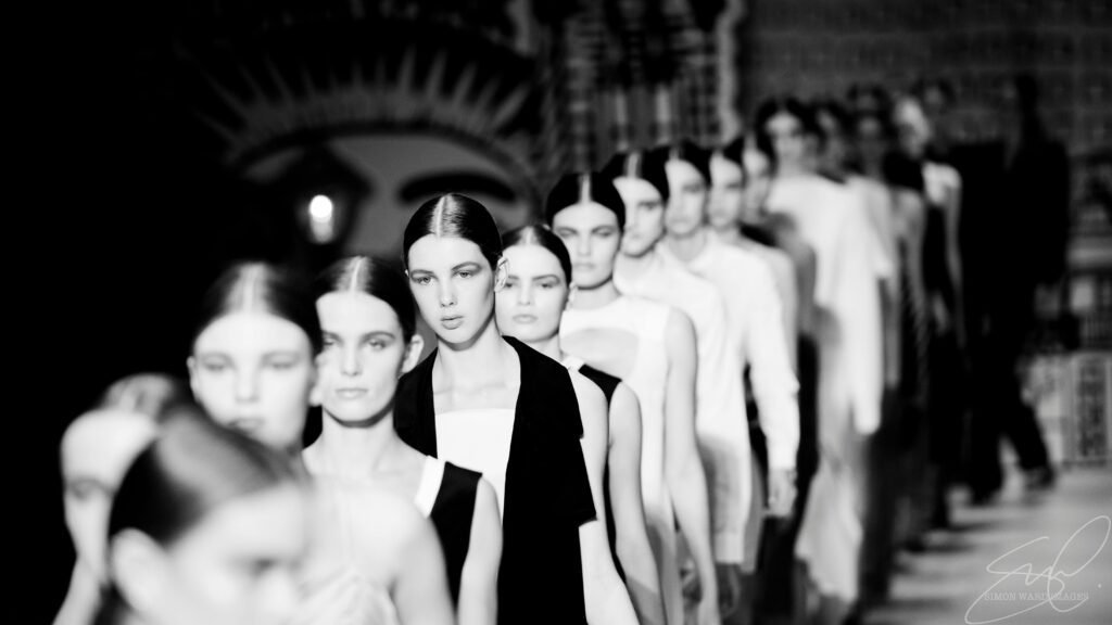 High contrast black and white image of models walking down the fashion runway.